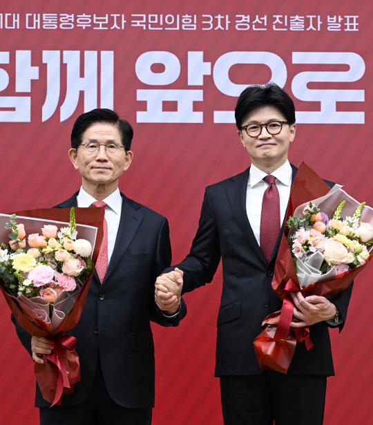 국민의힘 6·3 대선 3차 경선에 진출한 김문수(왼쪽부터)·한동훈 후보가 지난 4월29일 서울 여의도 당사에서 3차 경선 결과 발표 후 꽃다발을 들고서 기념촬영 하고 있다.<국회사진기자단·연합뉴스>
